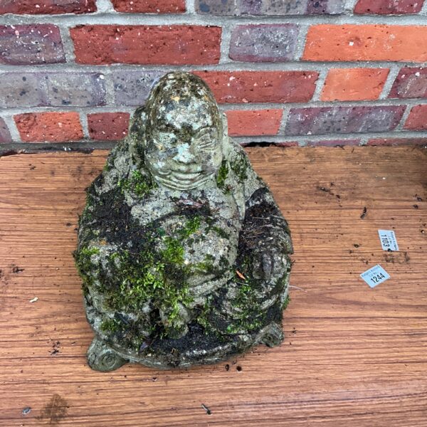 Weathered stone garden Buddha figurine with moss growth.