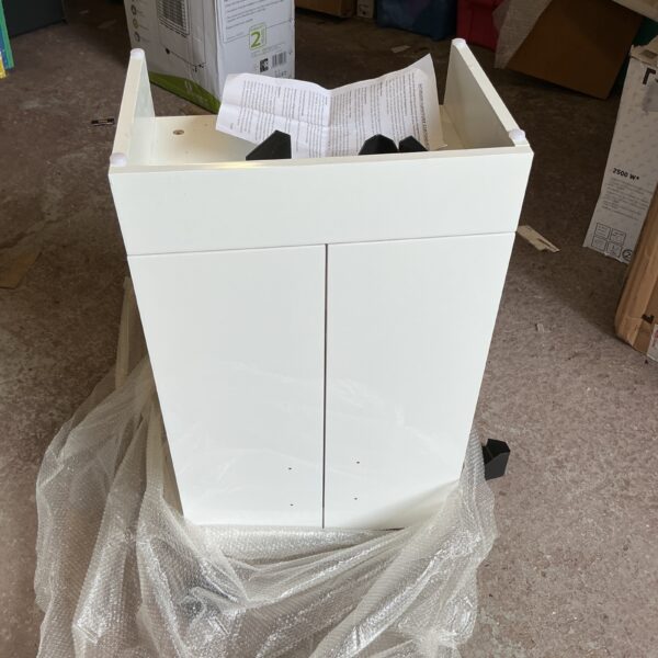 White cloakroom washbasin unit with protective packaging.