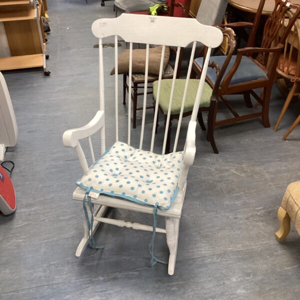 White painted wooden rocking chair with spindles and a seat cushion.