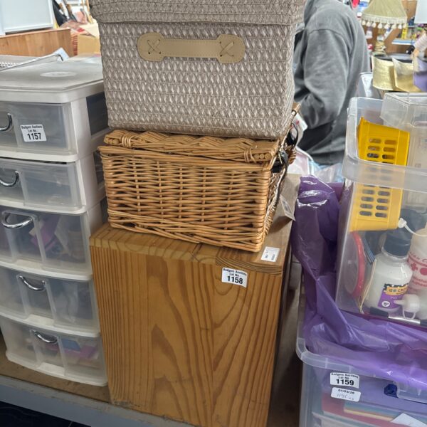 Set of three lidded wicker storage baskets on a wooden table.
