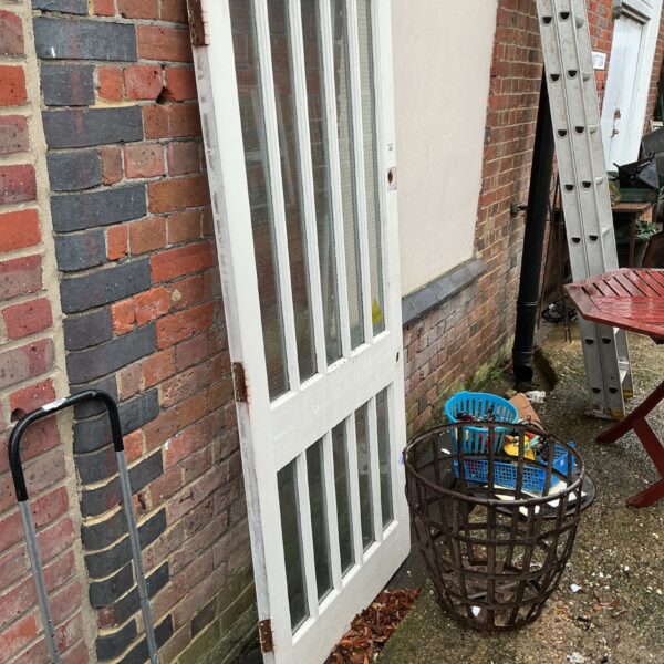 Salvaged wooden fire door with glazed panel, ideal for restoration.