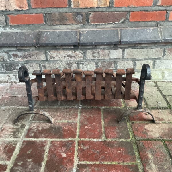 Antique wrought iron fireplace grate with decorative bars.