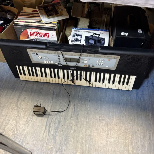 Yamaha PSR E203 electric keyboard with charger, side view.