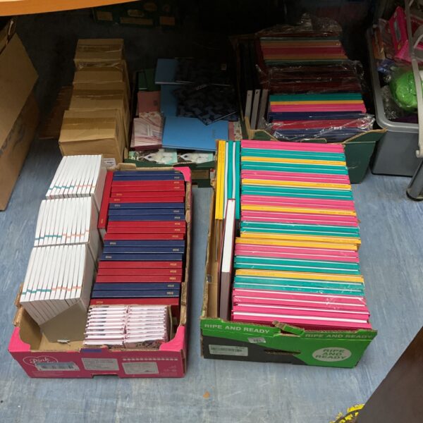 Large lot of 2026 notepads and diaries stacked in boxes.