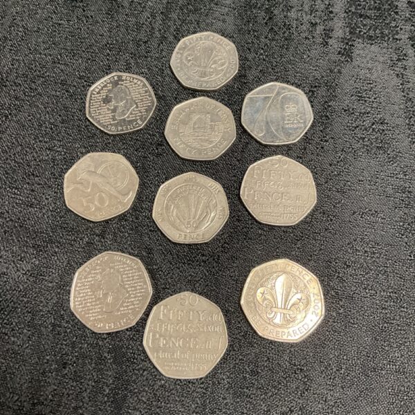 Collection of 50 pence commemorative coins, including Sherlock Holmes and Scout designs.