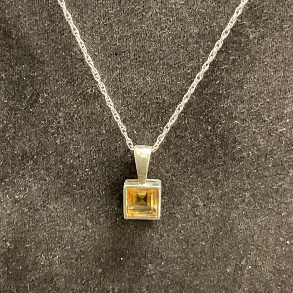 Close-up of 925 silver pendant with yellow citrine gemstone.
