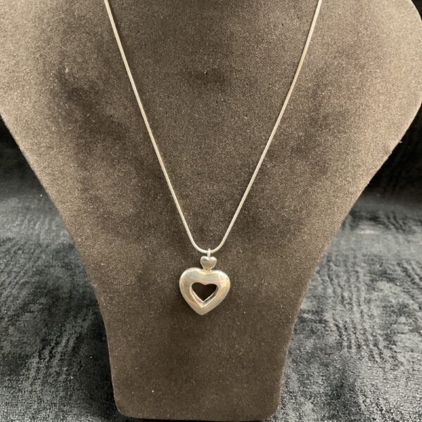 Close-up of 925 silver heart locket necklace on a display stand.