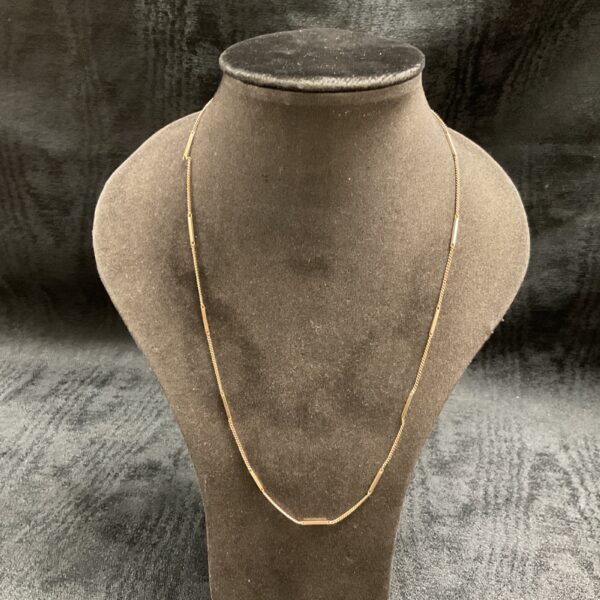 Delicate 9ct gold barlink necklace on a display stand.