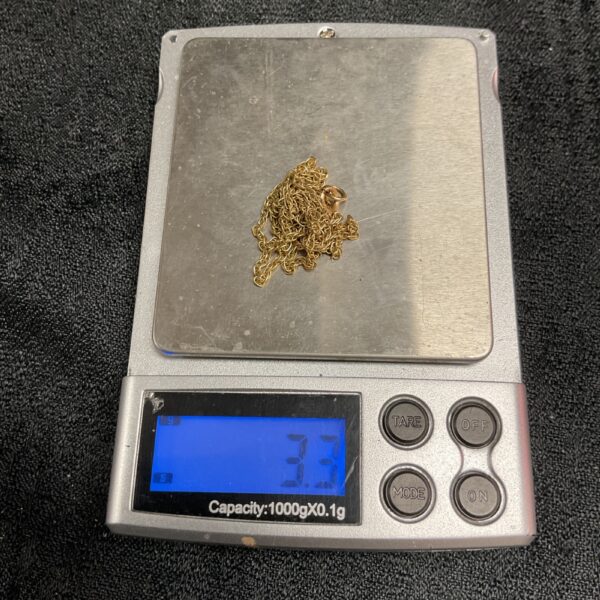 Broken 9ct gold necklace on a scale, showing weight.