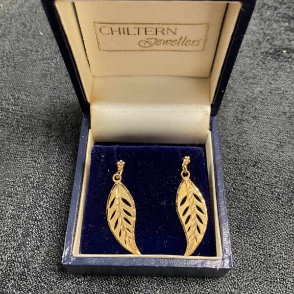 Close-up of 9ct gold leaf pattern stud earrings in a presentation box.
