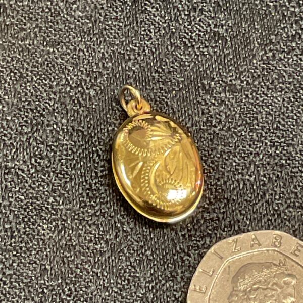 Close-up of 9ct gold locket pendant with embossed design.