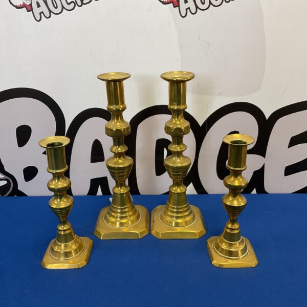Antique brass candlesticks displayed on a blue surface.