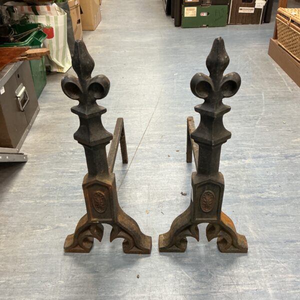 Antique cast iron fire dogs with fleur de lis design.