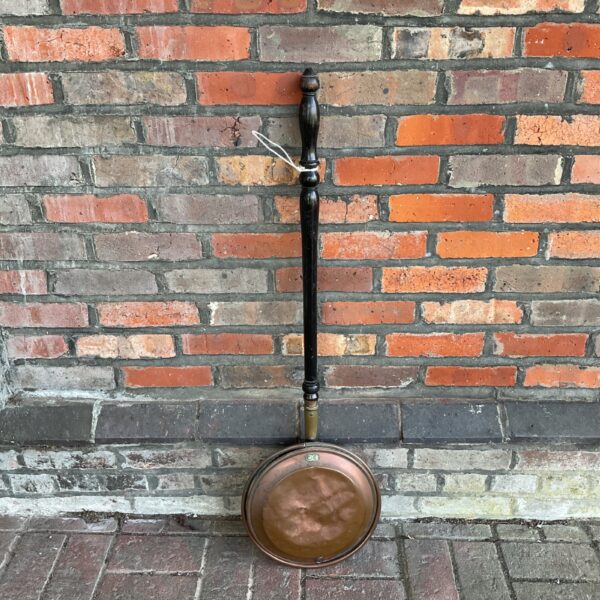 Antique copper bedpan with wooden handle, vintage medical collectible.