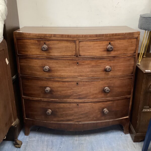 Antique mahogany bow front chest of drawers with decorative pulls.