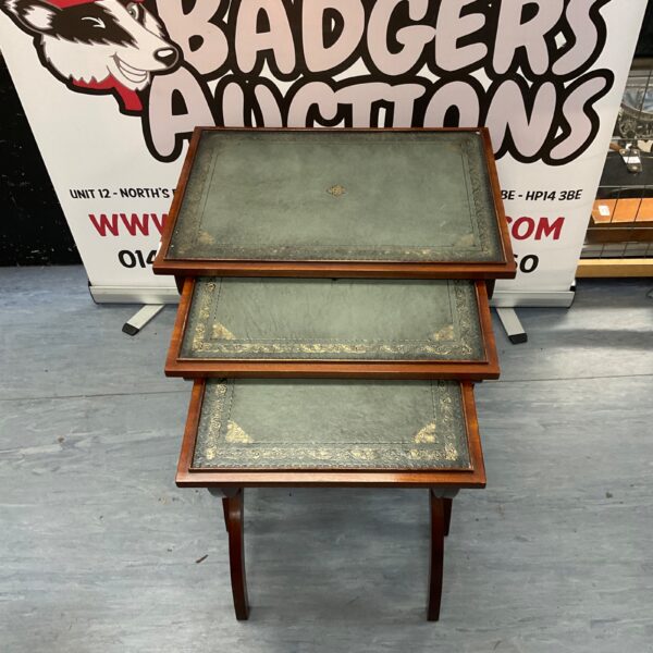 Antique mahogany nesting tables with leather tops and X-legs.