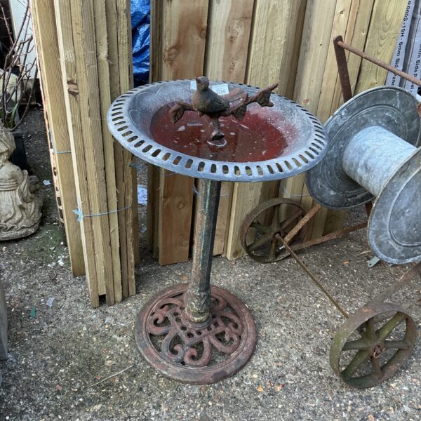 Antique metal bird bath in a garden setting.