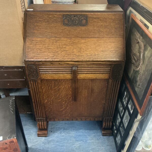 Intricately carved antique oak bureau with a sloping writing surface.