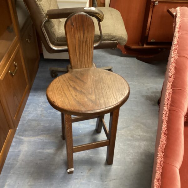Antique oak spinning chair with a circular seat and shaped backrest.