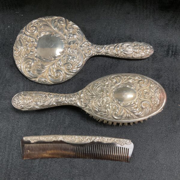 Antique sterling silver dressing table set with mirror, brush, and comb.
