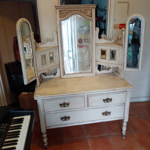 Antique tri-mirror dressing table with drawers and ornate detailing.