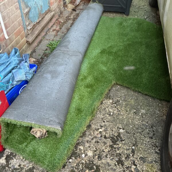 Roll of artificial grass in a garden setting.