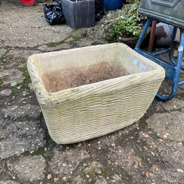 Vintage Arvec cast stone basket planter in a garden setting.