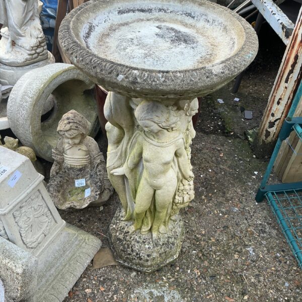 Vintage stone birdbath statue in a garden setting.