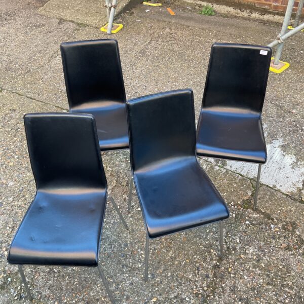 Set of four black dining chairs with chrome legs.