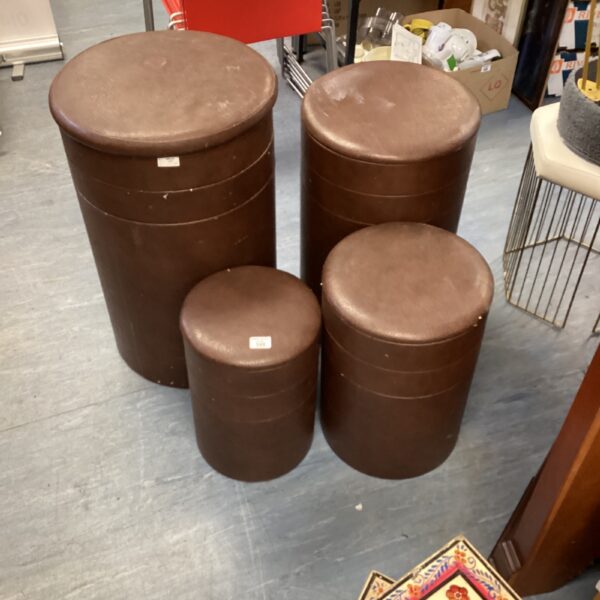 Four brown leather stools with a vintage aesthetic.