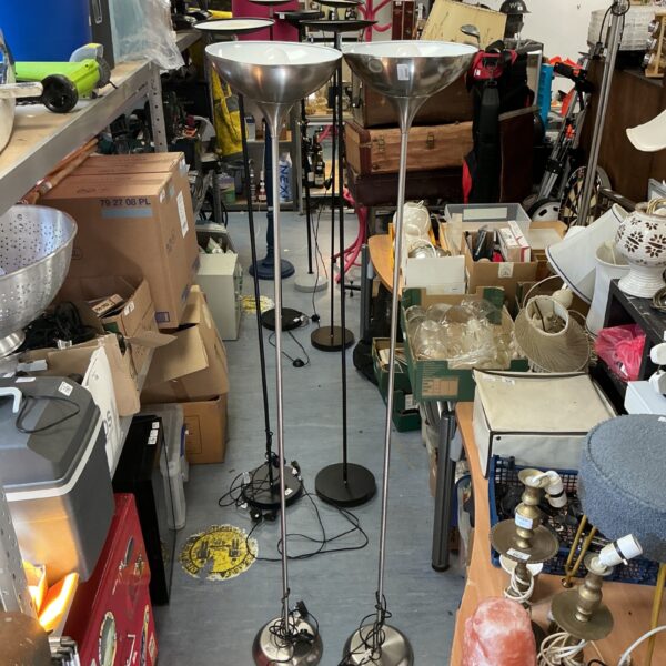 Pair of brushed steel uplighters in a cluttered room.