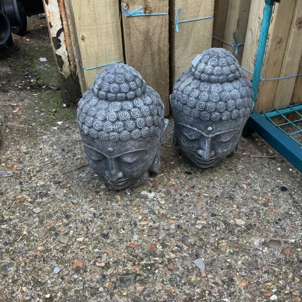 Pair of weathered stone Buddha garden statues in a garden setting.