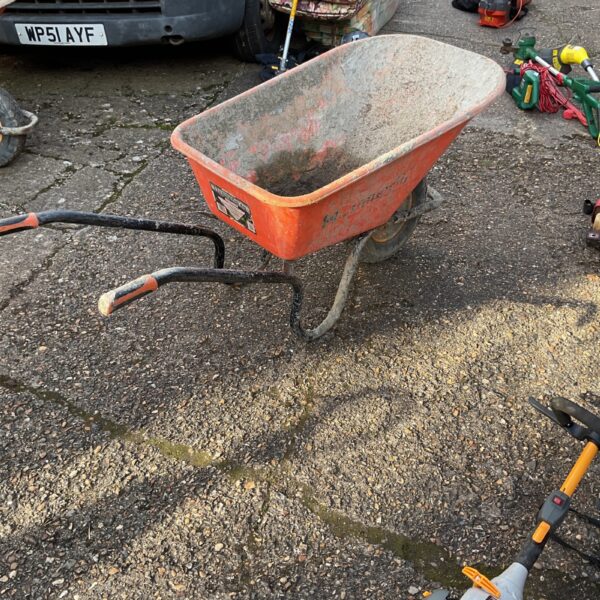 Well-used builders wheelbarrow in a garden setting.