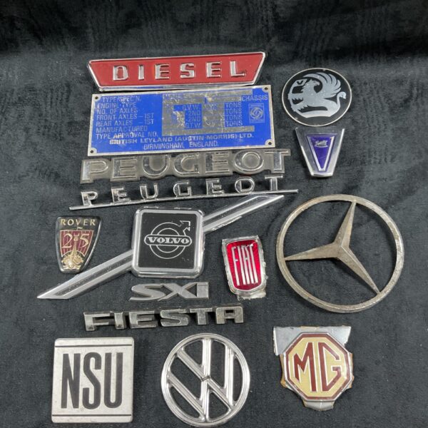 Vintage car badges and a blank chassis plate collection.