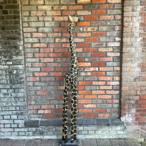 Full view of a large, intricately carved wooden giraffe sculpture.