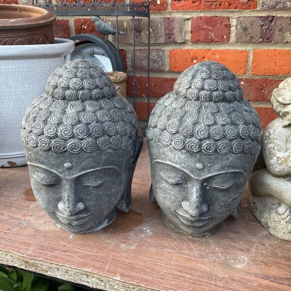 Pair of weathered cast stone Buddha heads for garden decor.