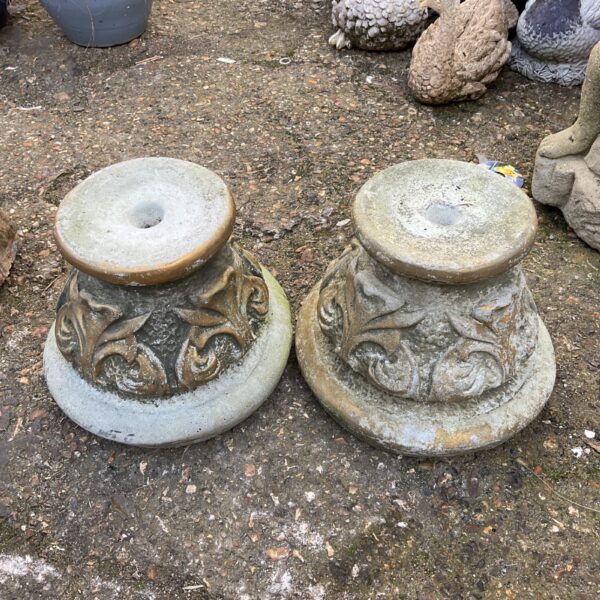 Two weathered cast stone garden pot stands for plant display.