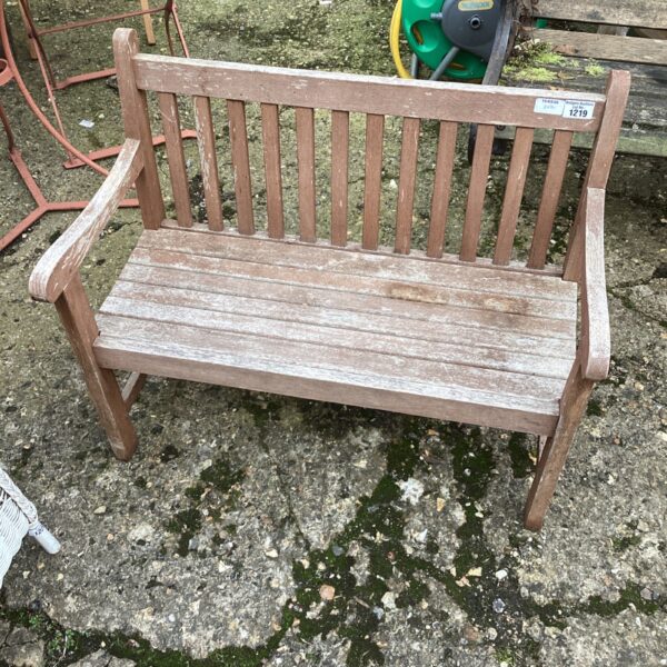 Rustic wooden child's garden bench in a garden setting.