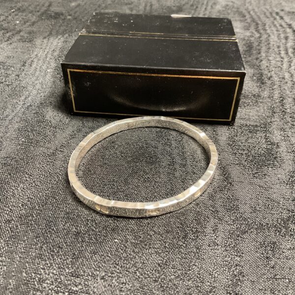 Silver Christian St. John millenium bracelet displayed on a dark cloth.