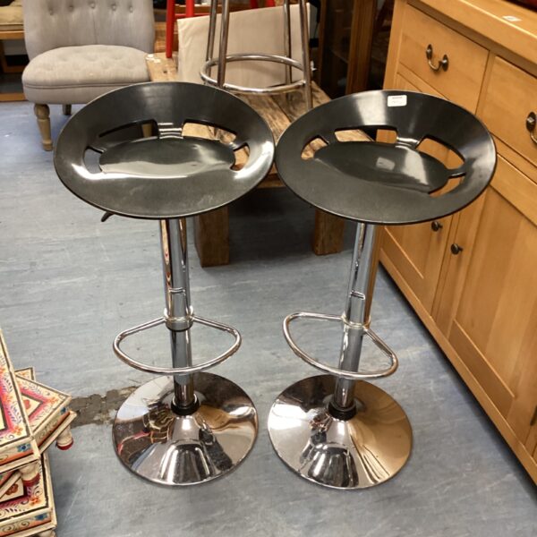 Pair of modern chrome bar stools with black seats.