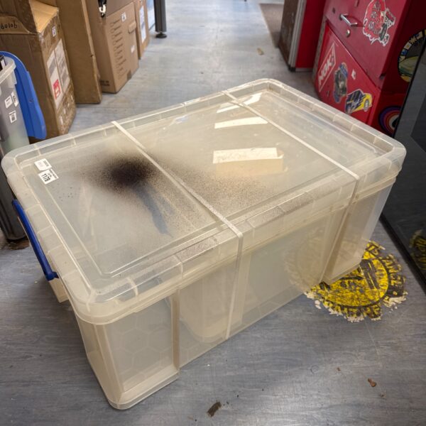 Clear plastic storage boxes stacked, showing spray paint on lid.