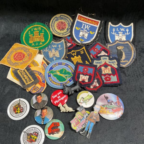 Vintage cloth and button badge collection featuring scouting and television themes.