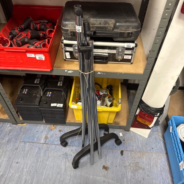 Collapsible metal clothes rail on wheels for garment storage.