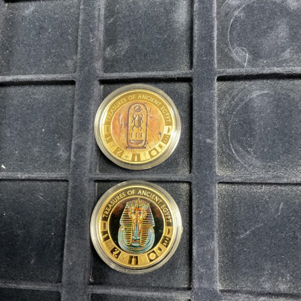 Close-up of Cook Islands gold plated coins with Egyptian hieroglyphs.