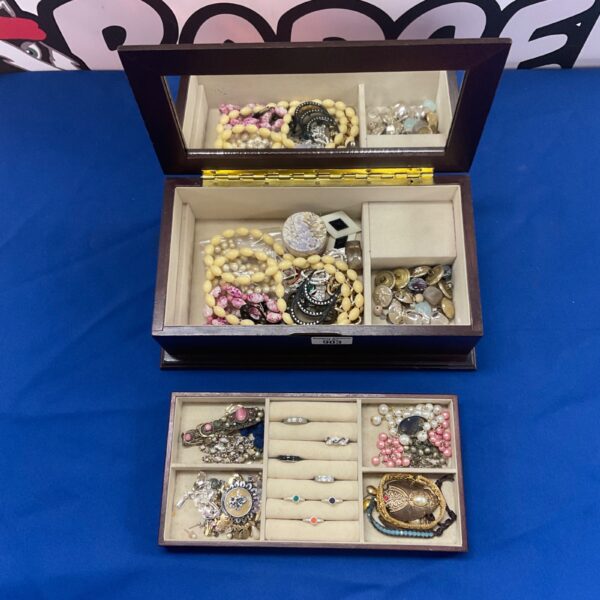 Wooden jewellery box filled with assorted costume jewellery pieces.
