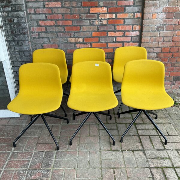 Set of six yellow Danish swivel chairs in a modern setting.