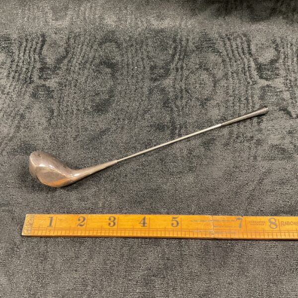 Silver miniature golf club driver on a white surface.