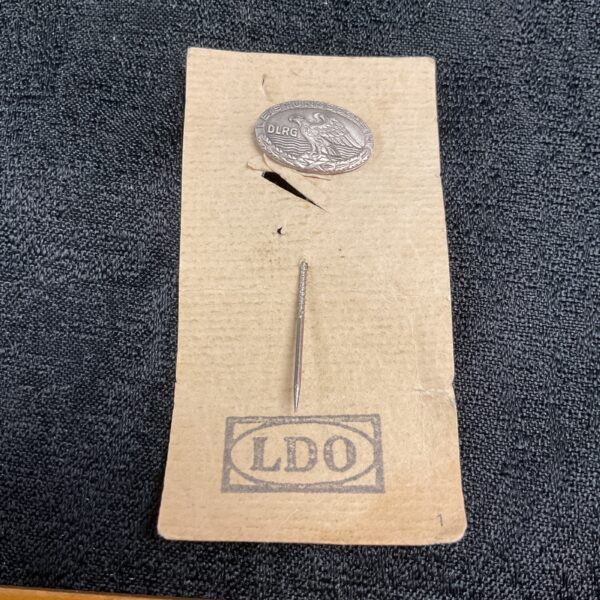 Vintage DLRG stick pin with detailed emblem on cardboard backing.