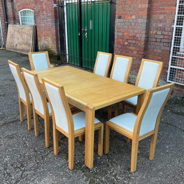 Ercol dining table and eight chairs in a modern dining setting.