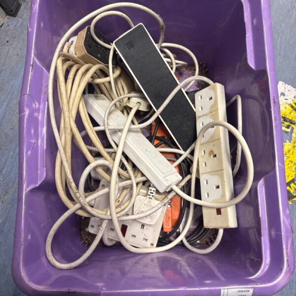Assorted extension leads and power strips in a plastic box.